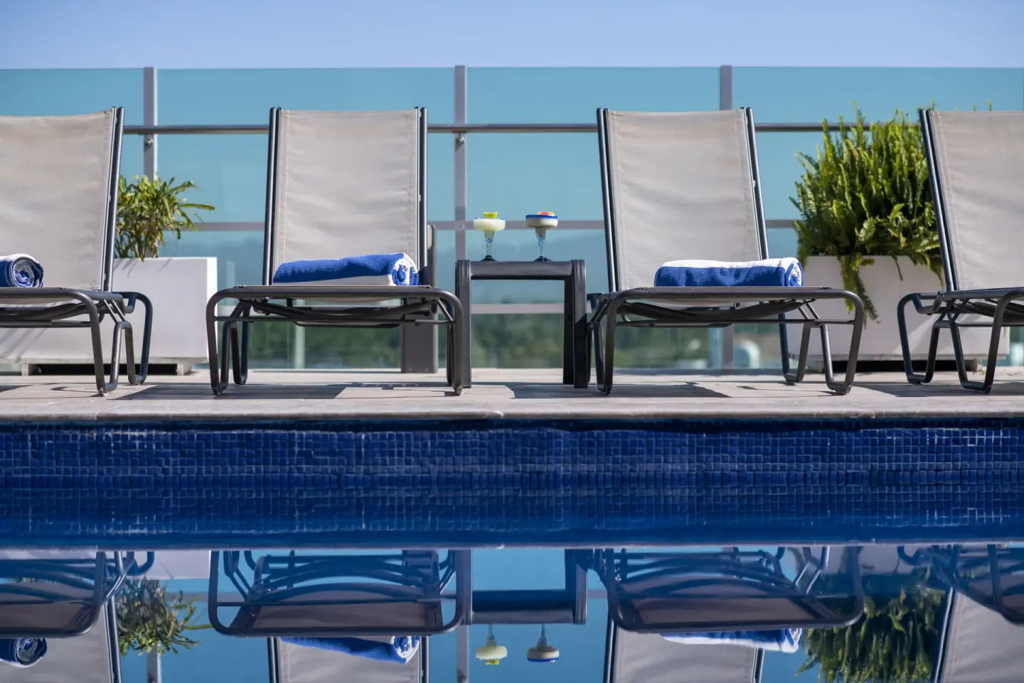 Poolside lounge chairs with rolled towels and drinks at Villa Varadero.