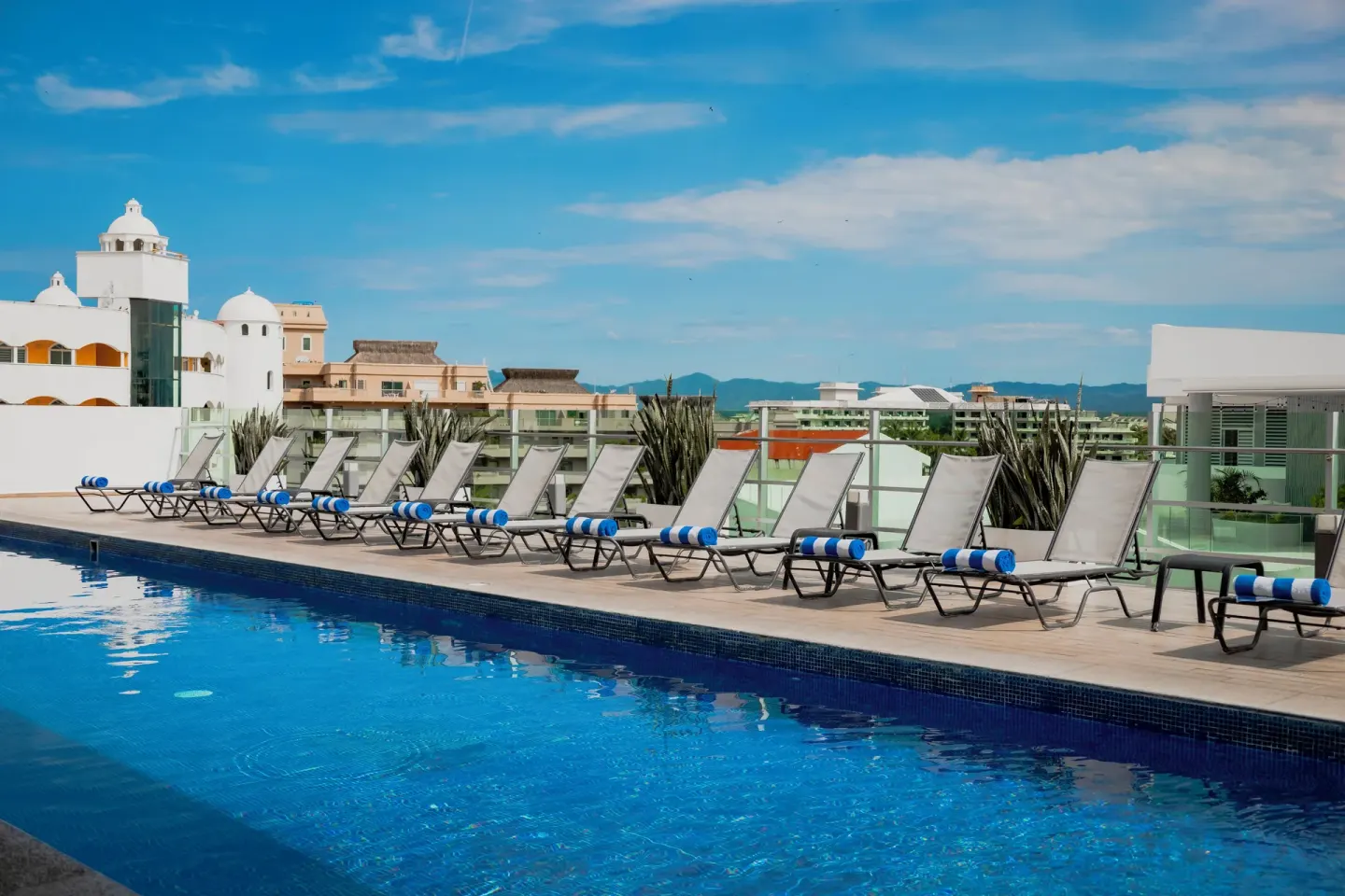 Rooftop pool deck with lounge chairs and nearby buildings at Villa Varadero.
