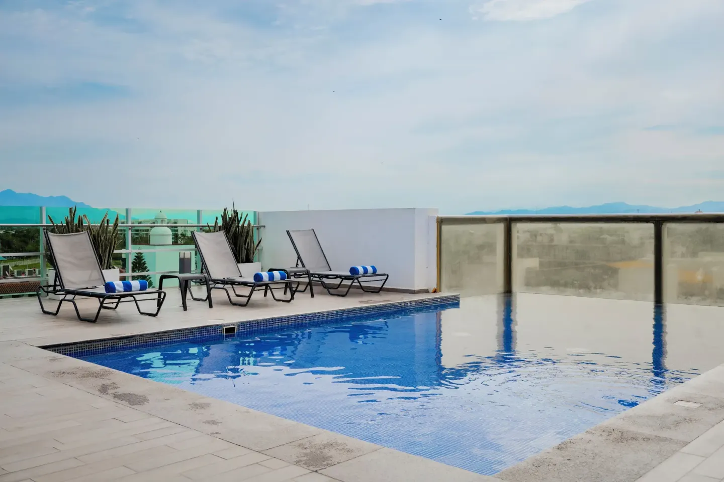 Rooftop pool with lounge chairs and blue towels at Villa Varadero.