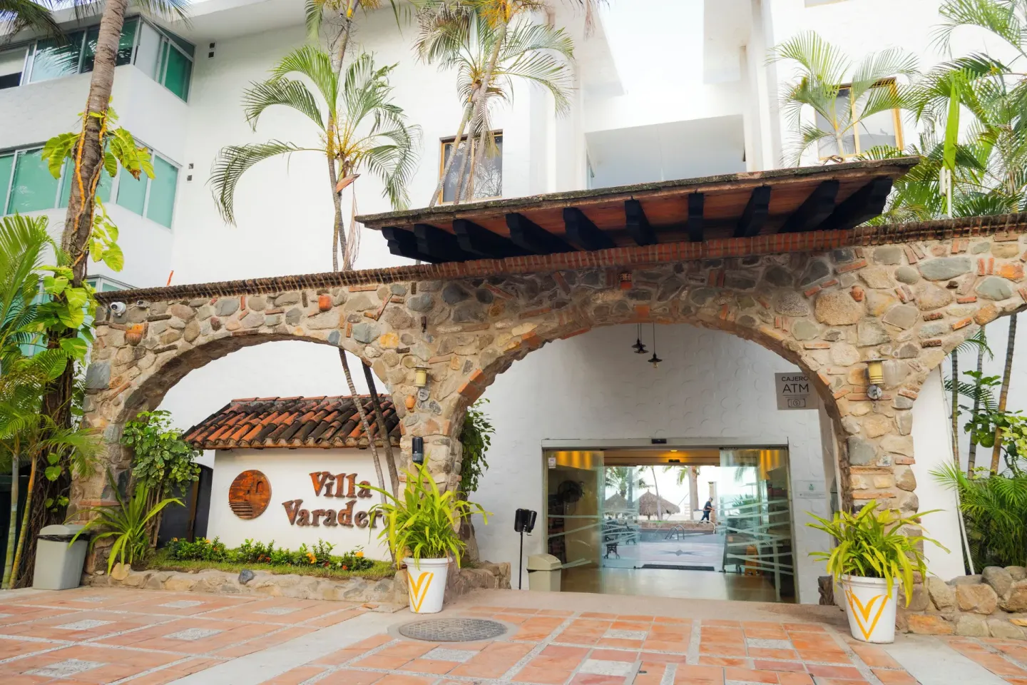 The Villa Varadero entrance has stone arches, tropical plants, and the hotel sign.