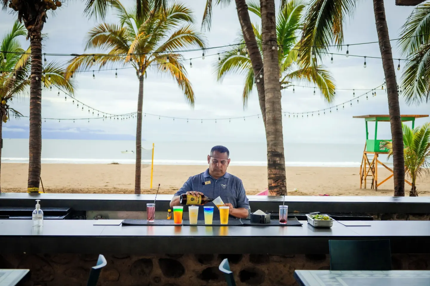 Bartender preparing colorful drinks at a beachfront bar at Villa Varadero.