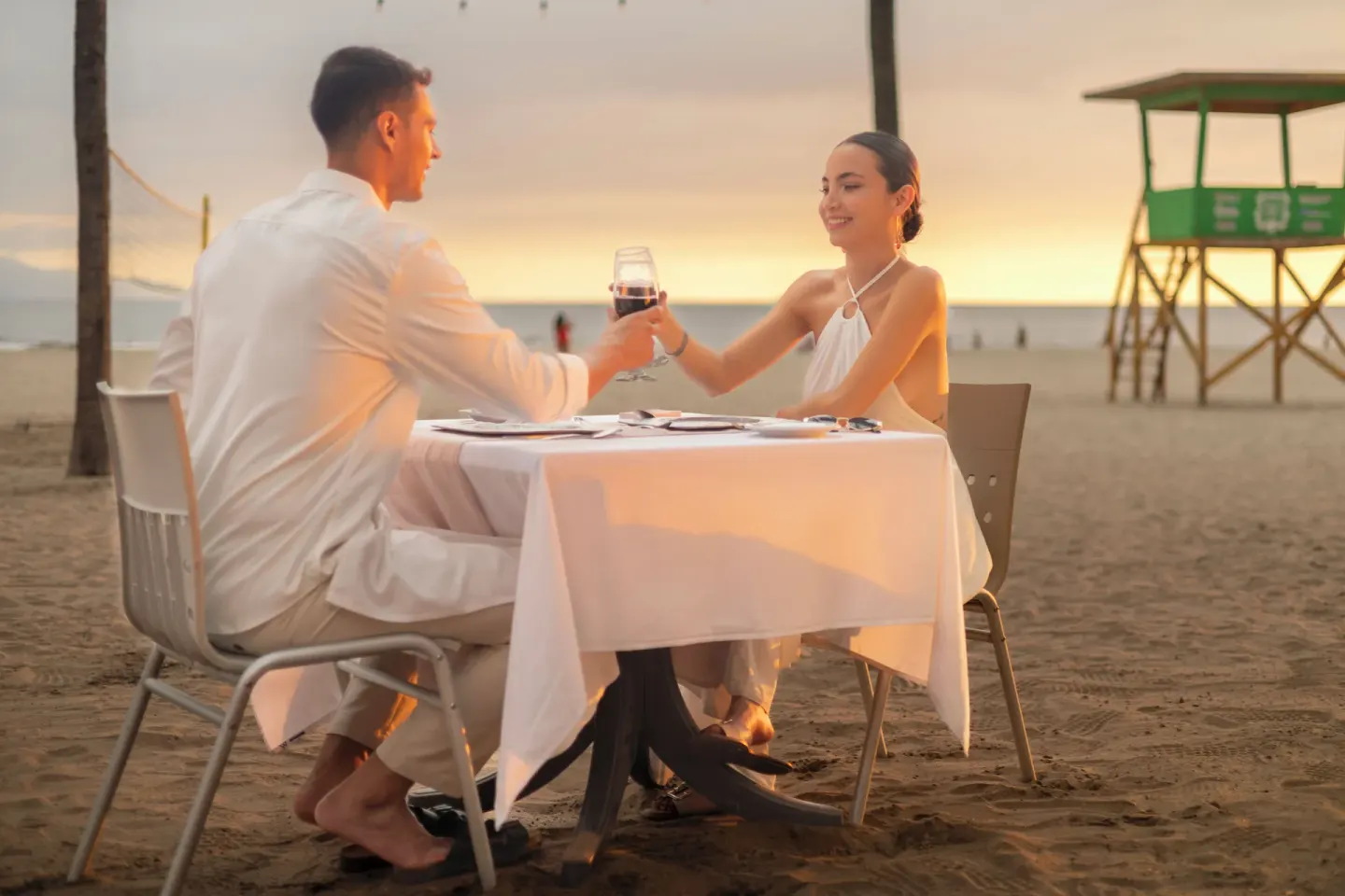 Couple toasting at a beach dinner table at sunset at Villa Varadero.