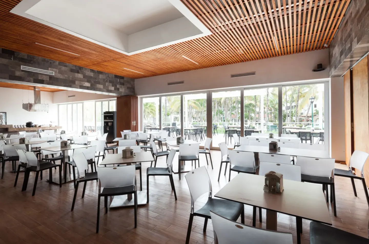 Bright dining room with white tables and garden-facing windows at Villa Varadero.