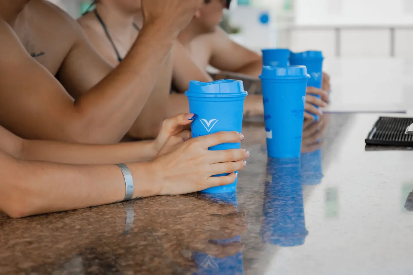Guests holding blue cups at a bar counter at Villa Varadero.