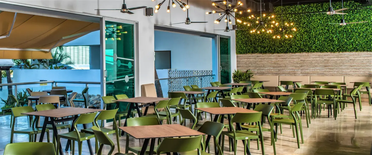 Dining area with green chairs, wood tables, and modern lighting at Villa Varadero.