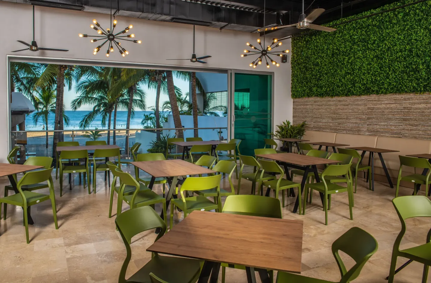 Dining room with green chairs and ocean views through wide openings at Villa Varadero.