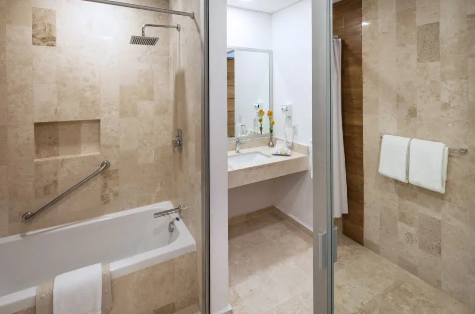 Deluxe room bathroom with tub, shower, vanity and towels at Villa Varadero.