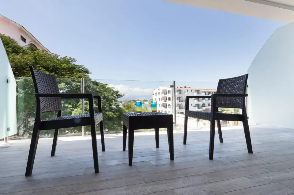 Private balcony with two chairs, a table and open sky views at Villa Varadero.