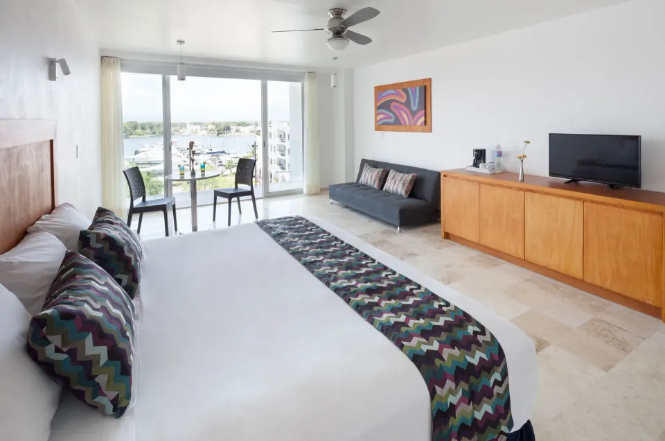 Deluxe Room with king bed and marina-facing balcony seating at Villa Varadero.