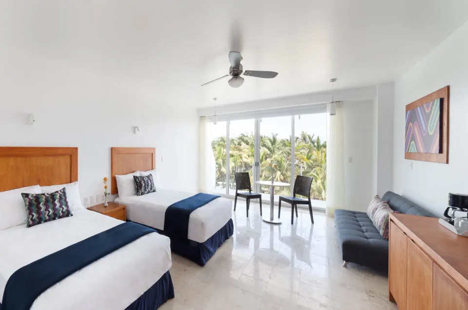 Deluxe Room with two beds and balcony seating by palm trees at Villa Varadero.