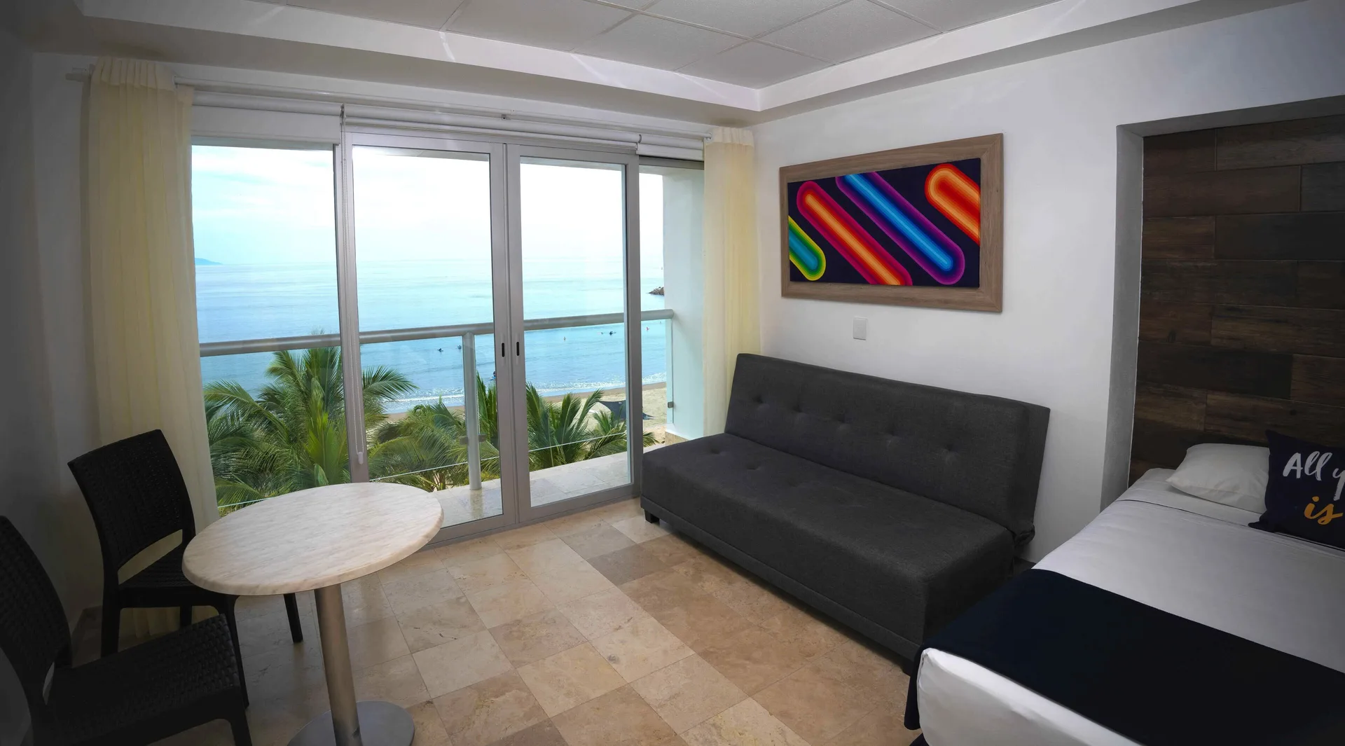 Junior room at Villa Varadero with one bed, sofa, table, balcony doors, and sea view.