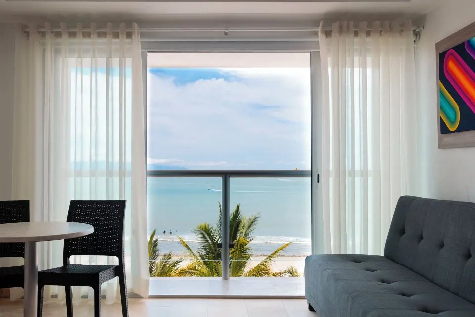 Junior room balcony doors frame an ocean view with sofa and table at Villa Varadero.