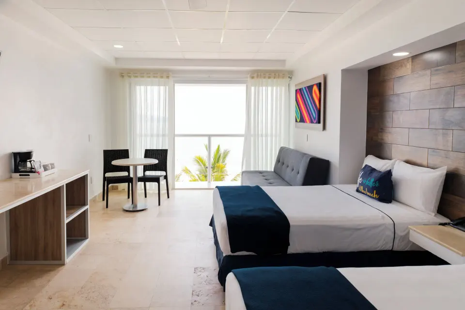 Junior room with two beds, sofa, dining table, and balcony doors at Villa Varadero.