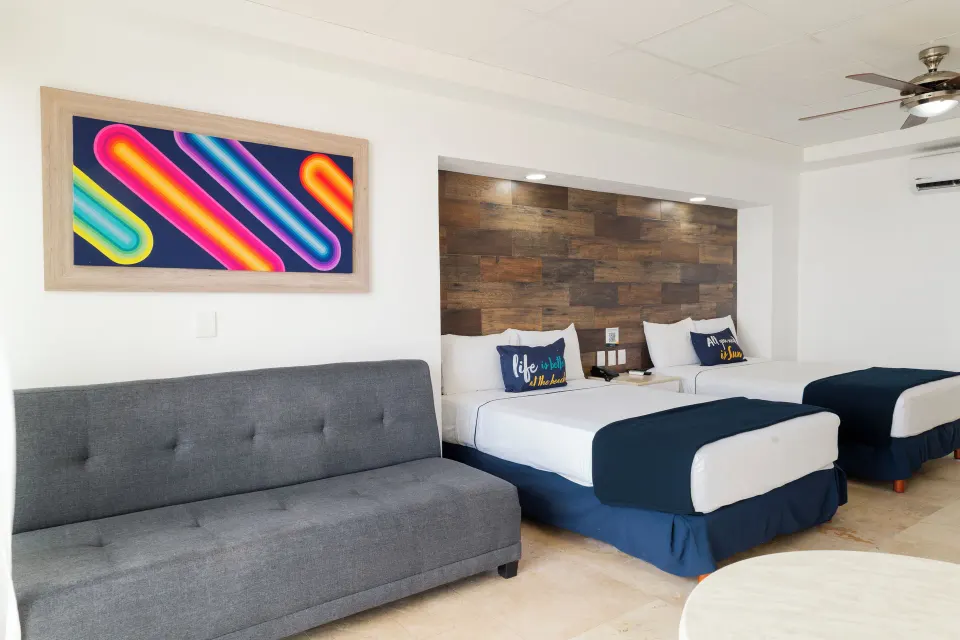 Junior room with two beds, gray sofa, wood headboard, and wall art at Villa Varadero.