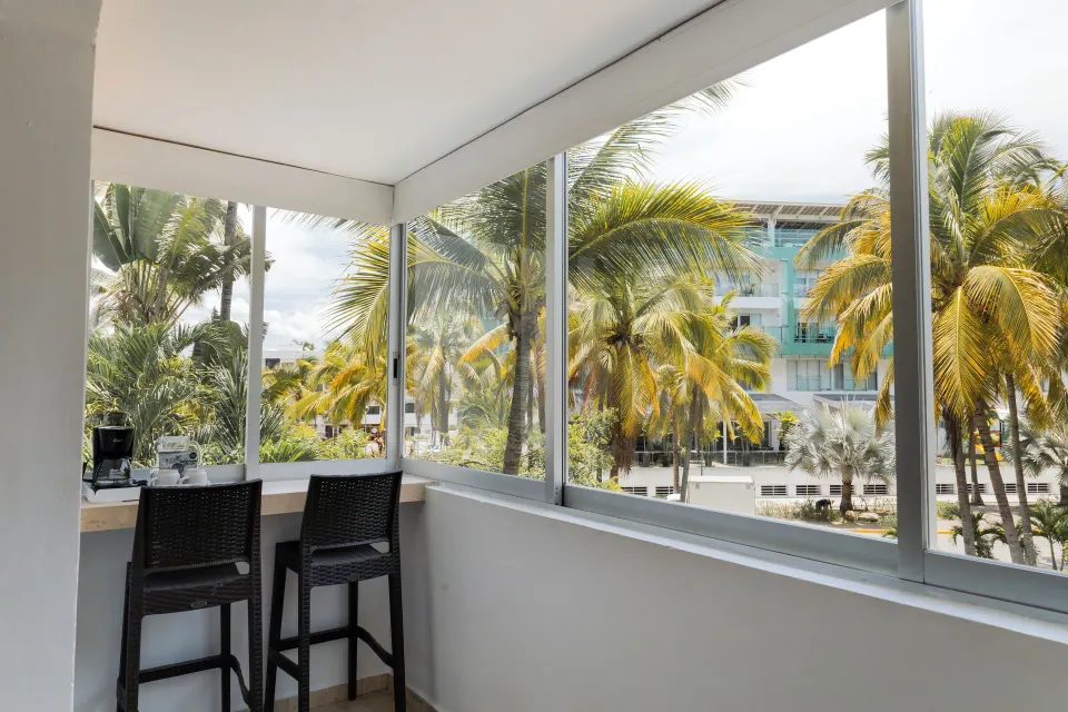 Standard Room balcony seating with palm and building views at Villa Varadero.