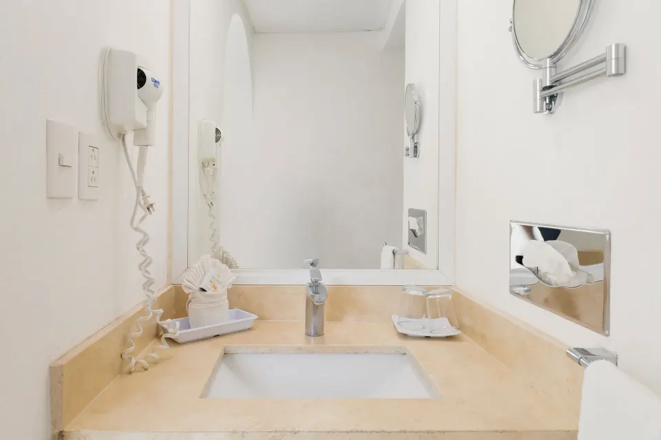 Standard Room bathroom vanity with sink, mirror and hair dryer at Villa Varadero.