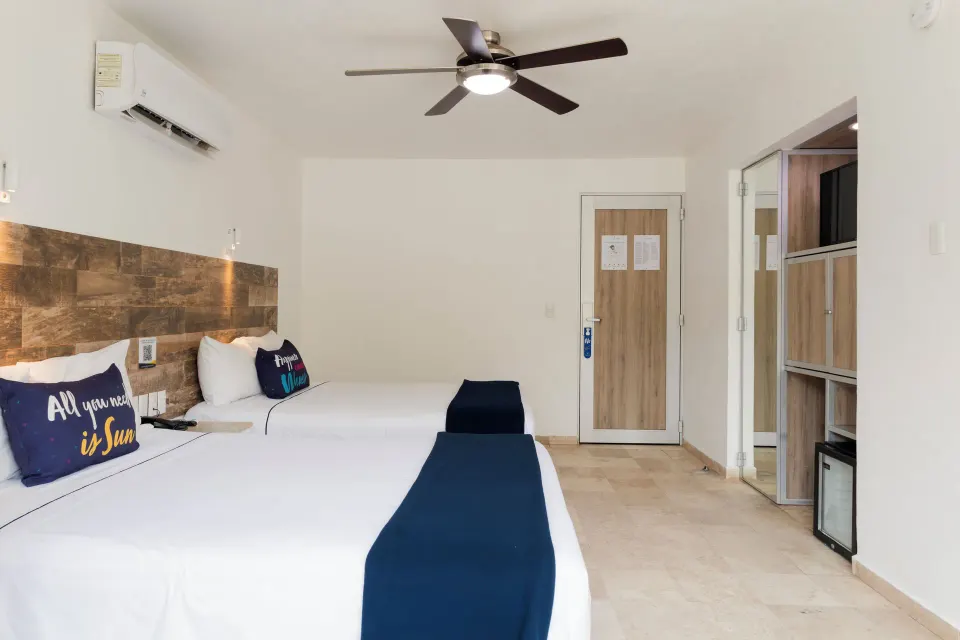 Standard Room at Villa Varadero with two beds, entry door, closet, TV, and mini fridge.