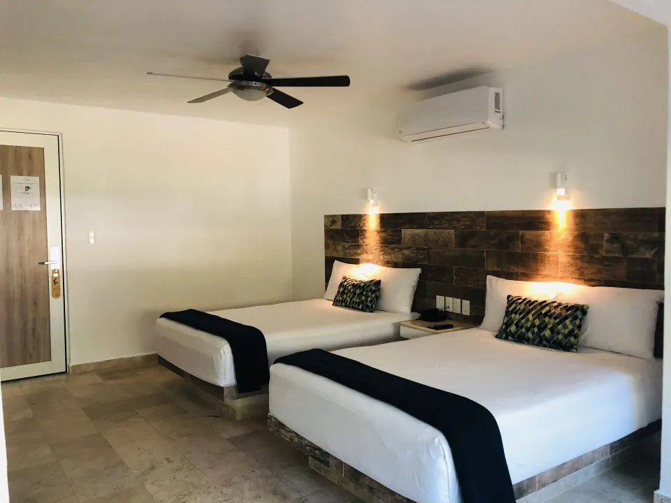 Standard Room at Villa Varadero with two beds, wall lights, ceiling fan, and air conditioner.