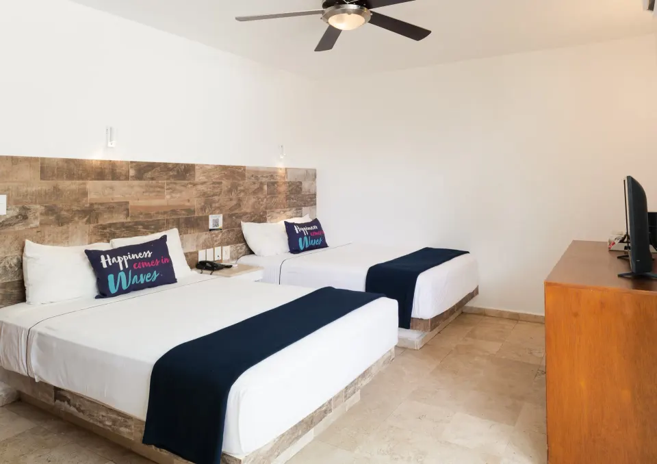 Standard Room at Villa Varadero with two beds, dark runners, tiled headboard, and TV on a wooden dresser.