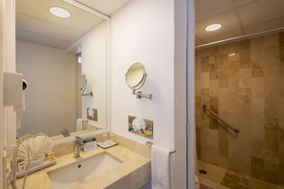 Superior Sea View room bathroom with vanity, mirror, and tiled shower at Villa Varadero.