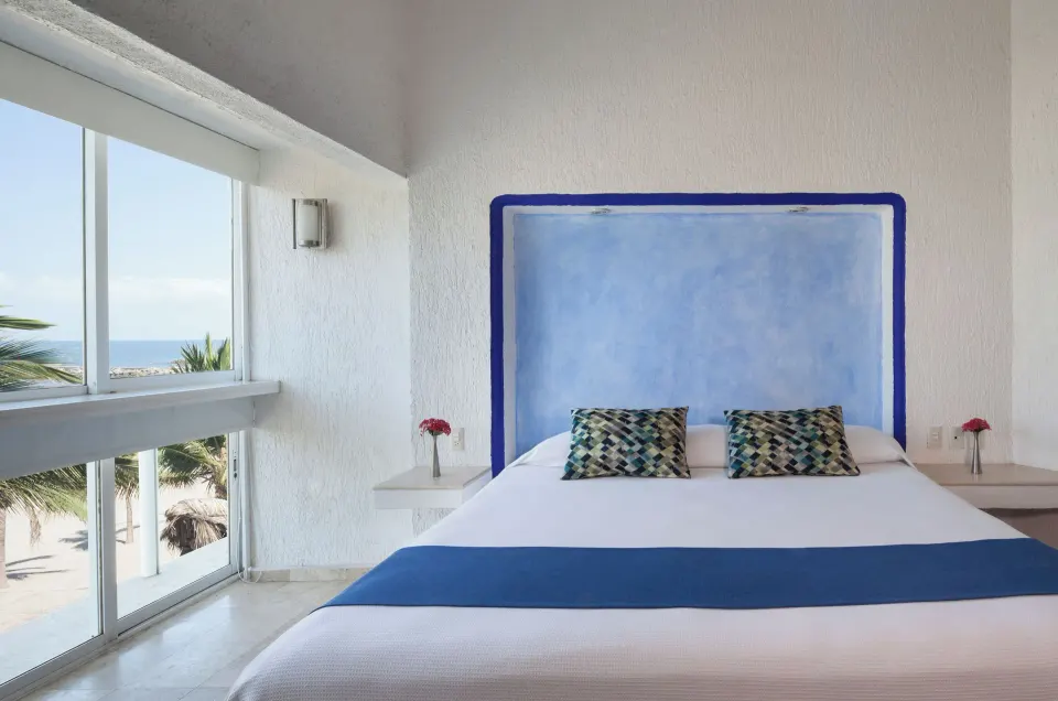 Superior Sea View room with king bed, blue runner, and ocean view window at Villa Varadero.