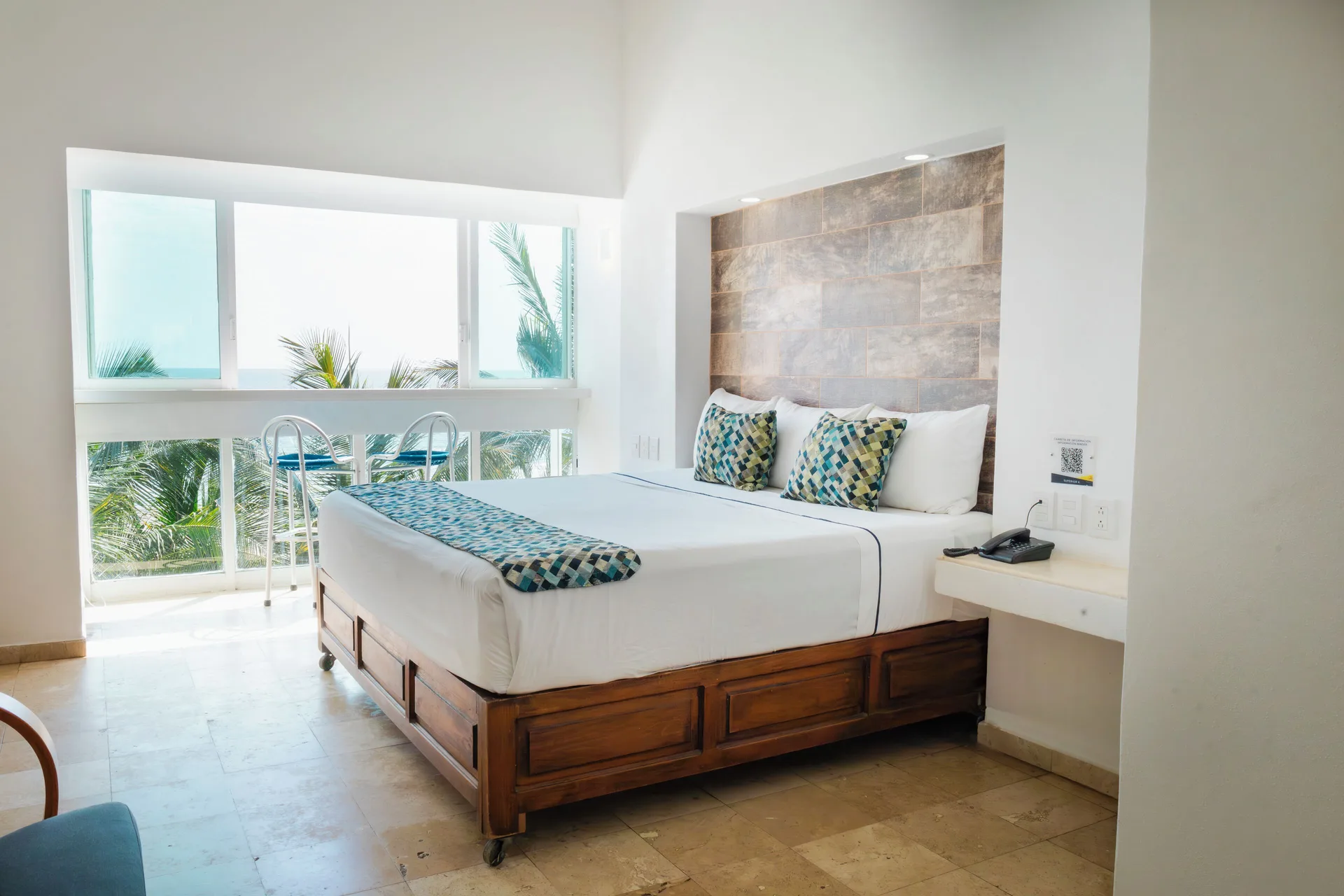 Superior Sea View room with king bed, tiled headboard, and palm-framed window at Villa Varadero.
