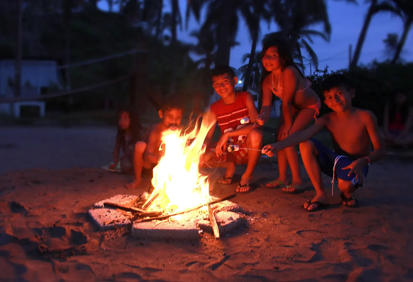Children roasting marshmallows at a beach bonfire at Vista Playa de Oro Manzanillo.