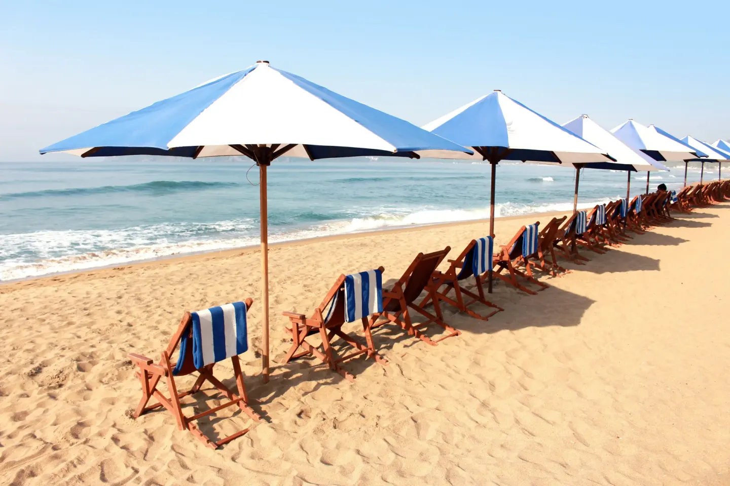Beach loungers and white umbrellas beside the ocean at Vista Playa de Oro Manzanillo.