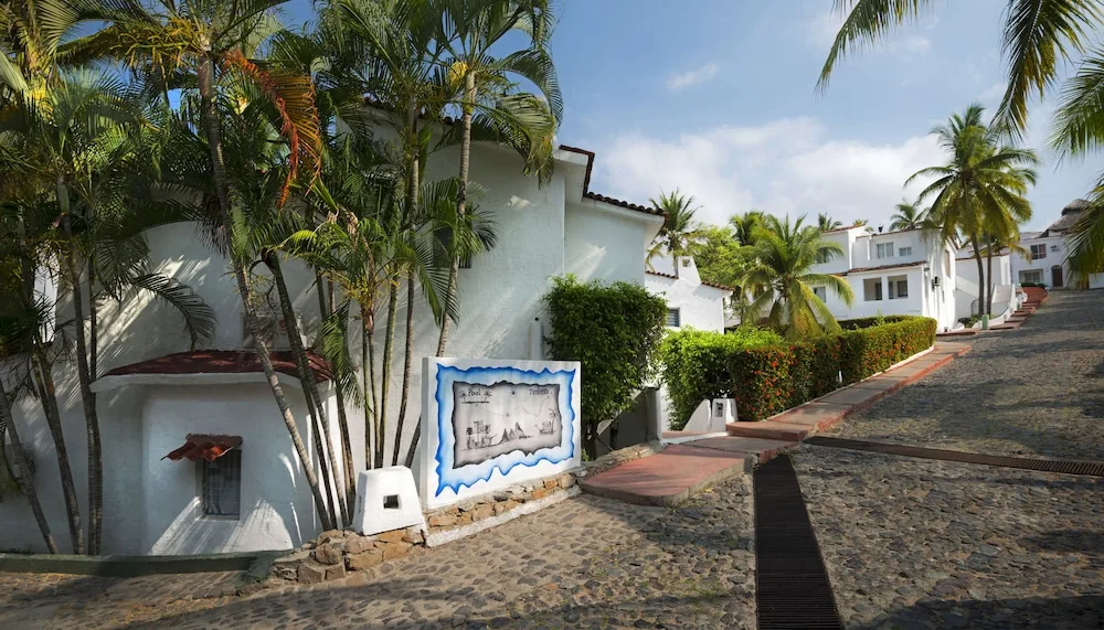 Cobblestone road and white resort buildings among palms at Vista Playa de Oro Manzanillo.