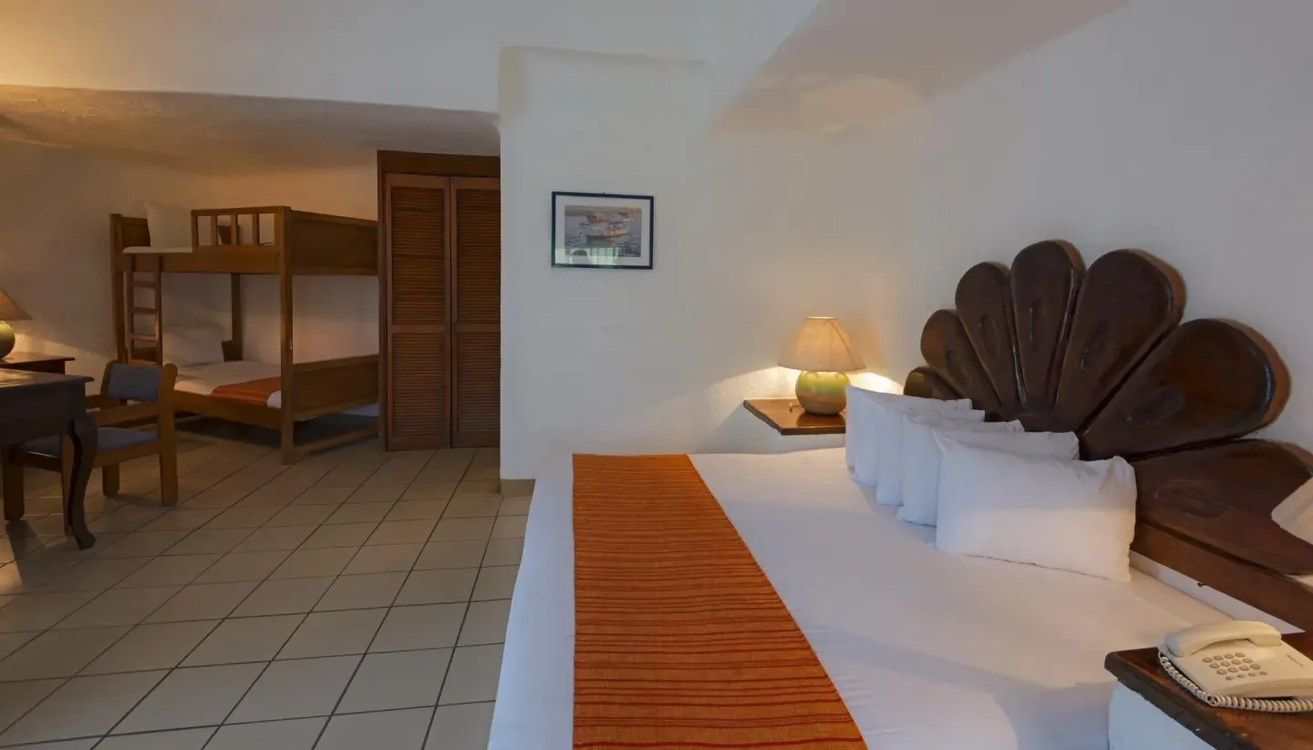 Guest room with king bed and bunk beds at Vista Playa de Oro Manzanillo.