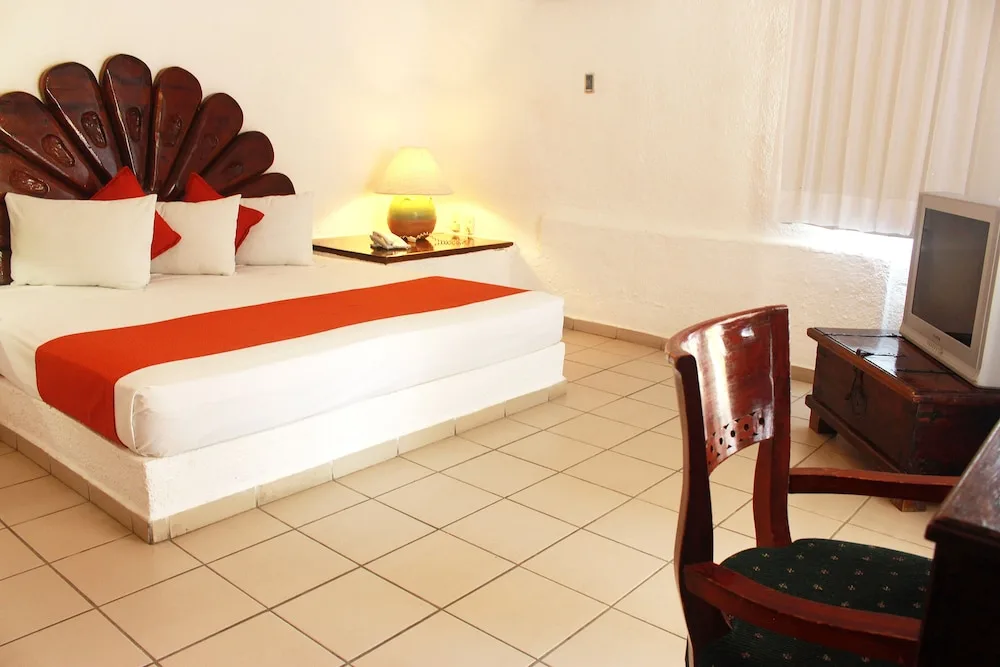 King-bed guest room with carved headboard at Vista Playa de Oro Manzanillo.