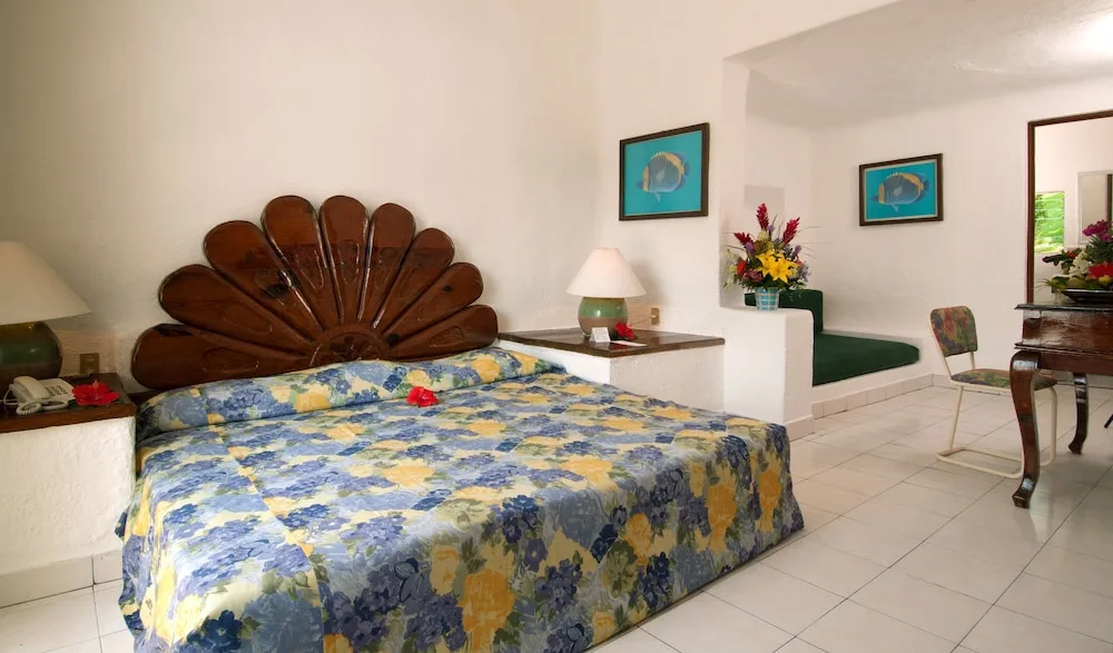 King bed guest room with floral bedding and sitting nook at Vista Playa de Oro Manzanillo.