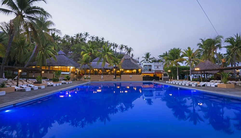 Large resort pool at dusk with palm trees at Vista Playa de Oro Manzanillo.