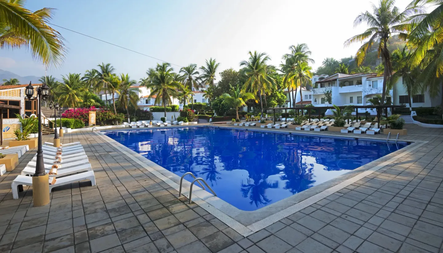 Large rectangular pool with lounge chairs and palms at Vista Playa de Oro Manzanillo.