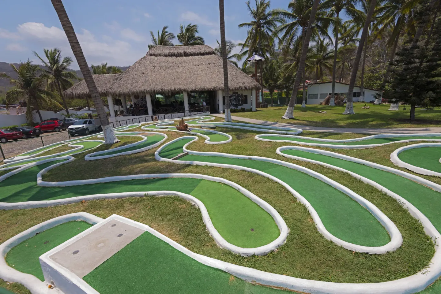 Mini-golf course with palms and a thatched pavilion at Vista Playa de Oro Manzanillo.