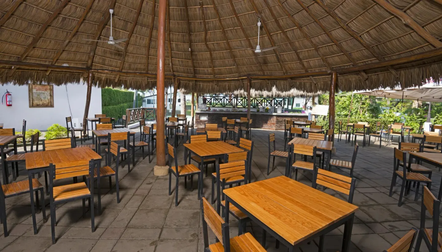 Open-air palapa seating area with wooden tables at Vista Playa de Oro Manzanillo.