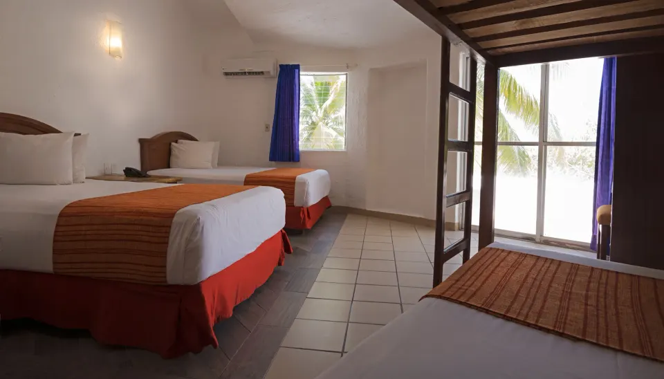 Family Room with multiple beds and balcony doors at Vista Playa de Oro Manzanillo.