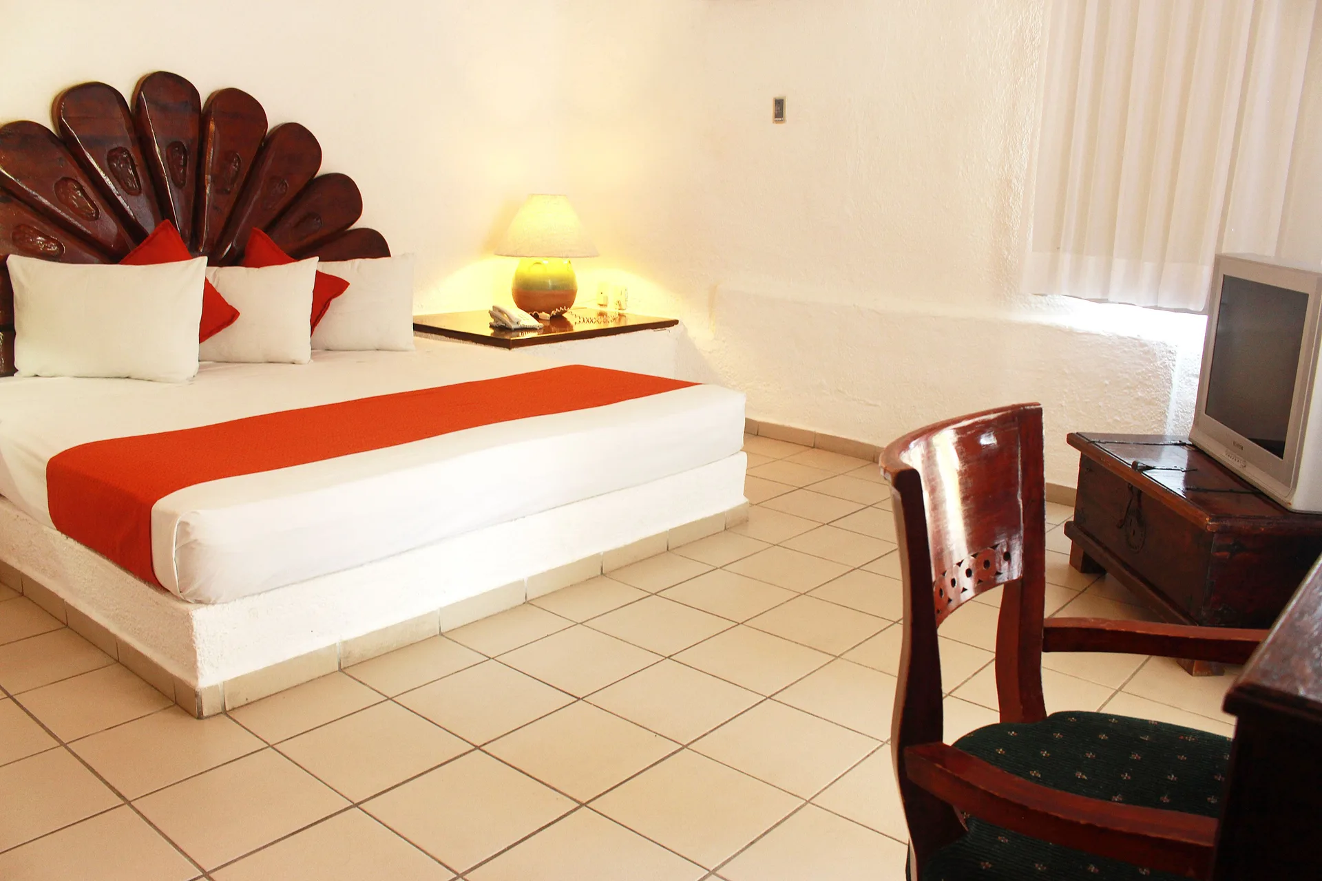 Standard Room king bed with seating area and television at Vista Playa de Oro Manzanillo.