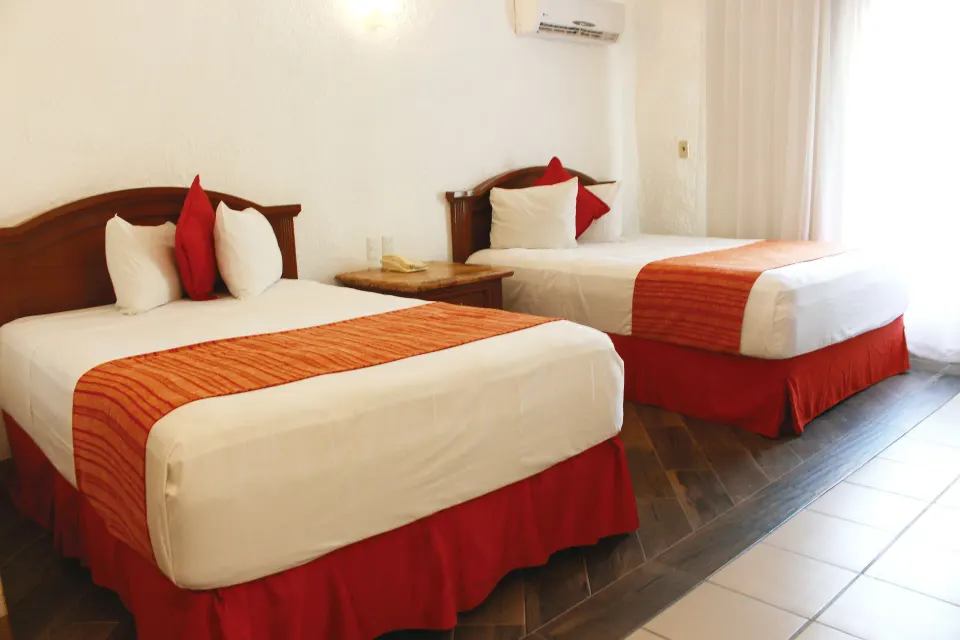 Standard Room with two double beds and red accents at Vista Playa de Oro Manzanillo.