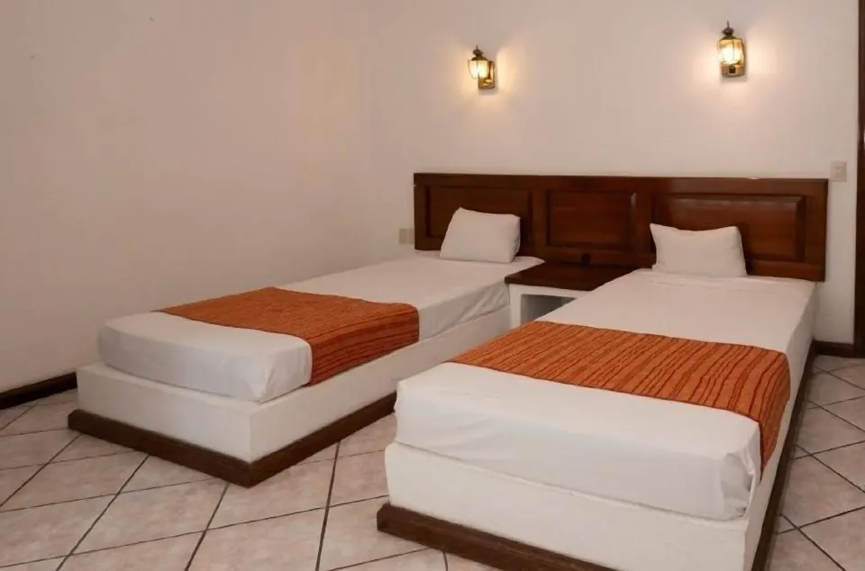 Standard Room with two twin beds and wall lamps at Vista Playa de Oro Manzanillo.