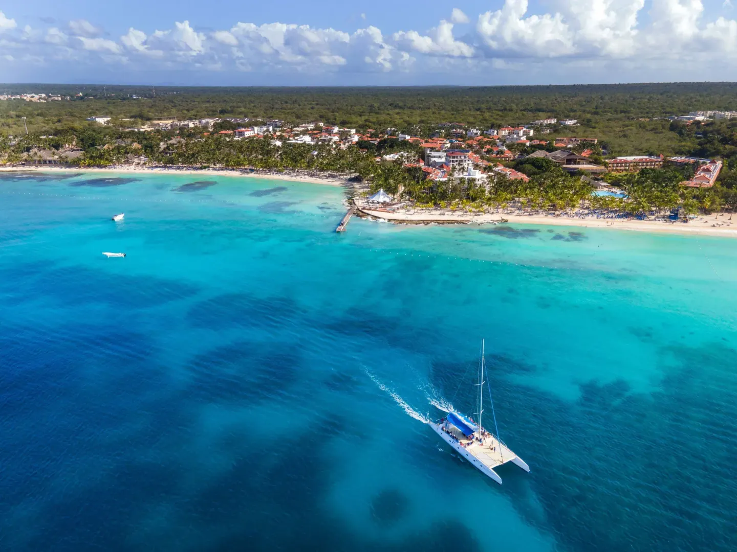 A catamaran sails offshore from the beach at Viva Dominicus Palace.