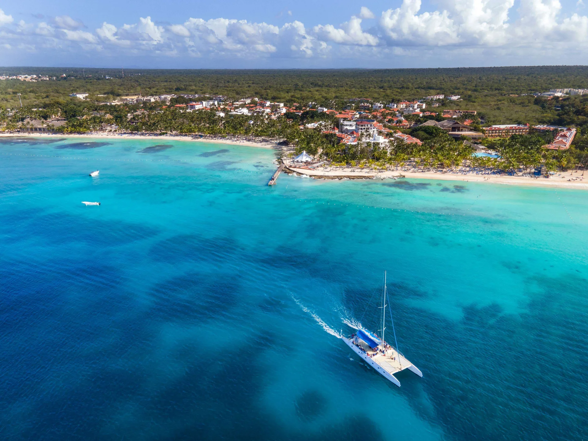 A catamaran sails offshore from the beach at Viva Dominicus Palace.