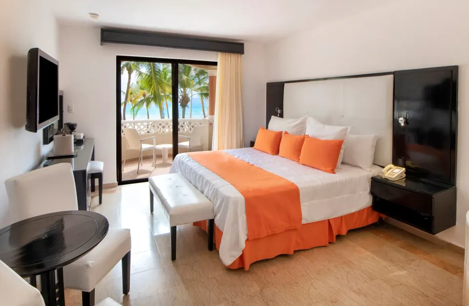 King bed guest room with balcony seating and ocean view at Viva Dominicus Palace.
