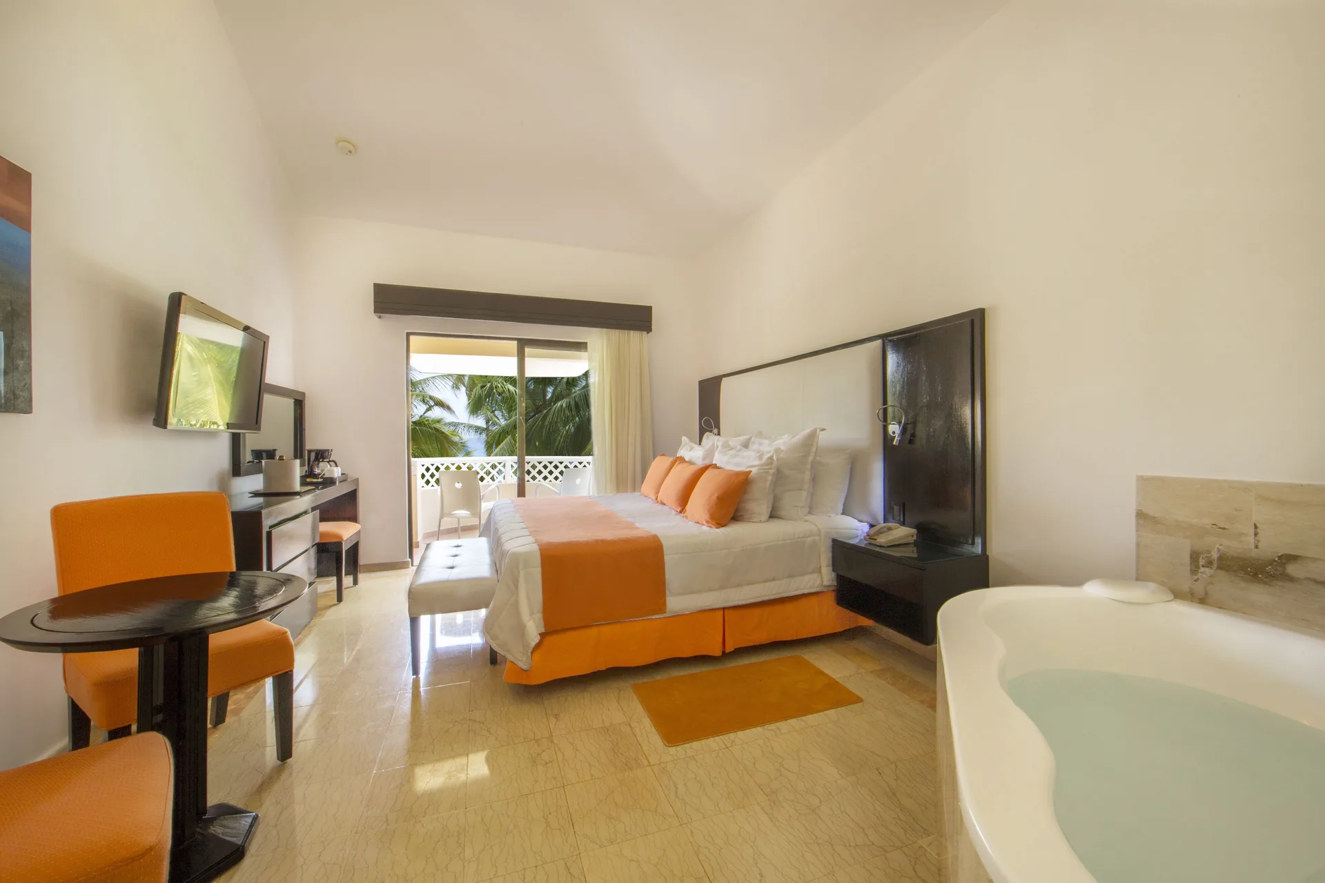 Guest room with king bed, balcony, and white soaking tub at Viva Dominicus Palace.