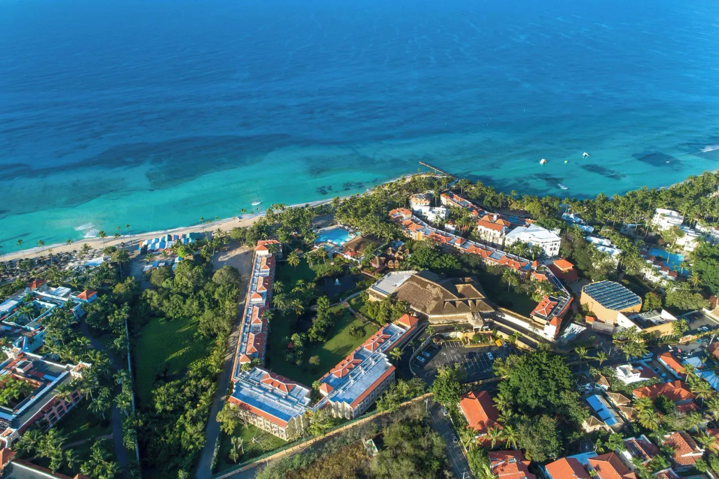 Wide aerial view of resort buildings, gardens, beach, and blue sea at Viva Dominicus Palace.