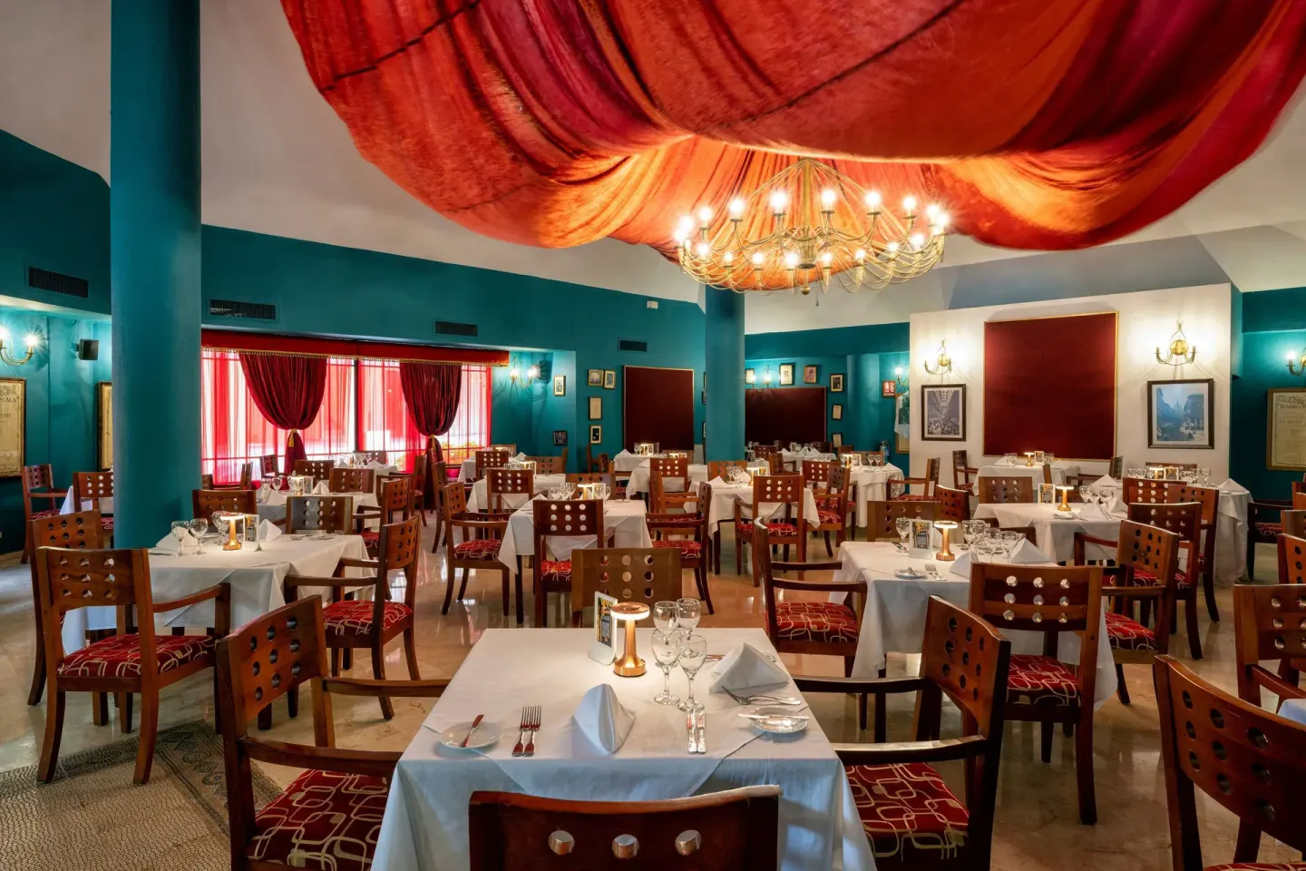 Elegant dining room with red ceiling drapery and teal walls at Viva Dominicus Palace.