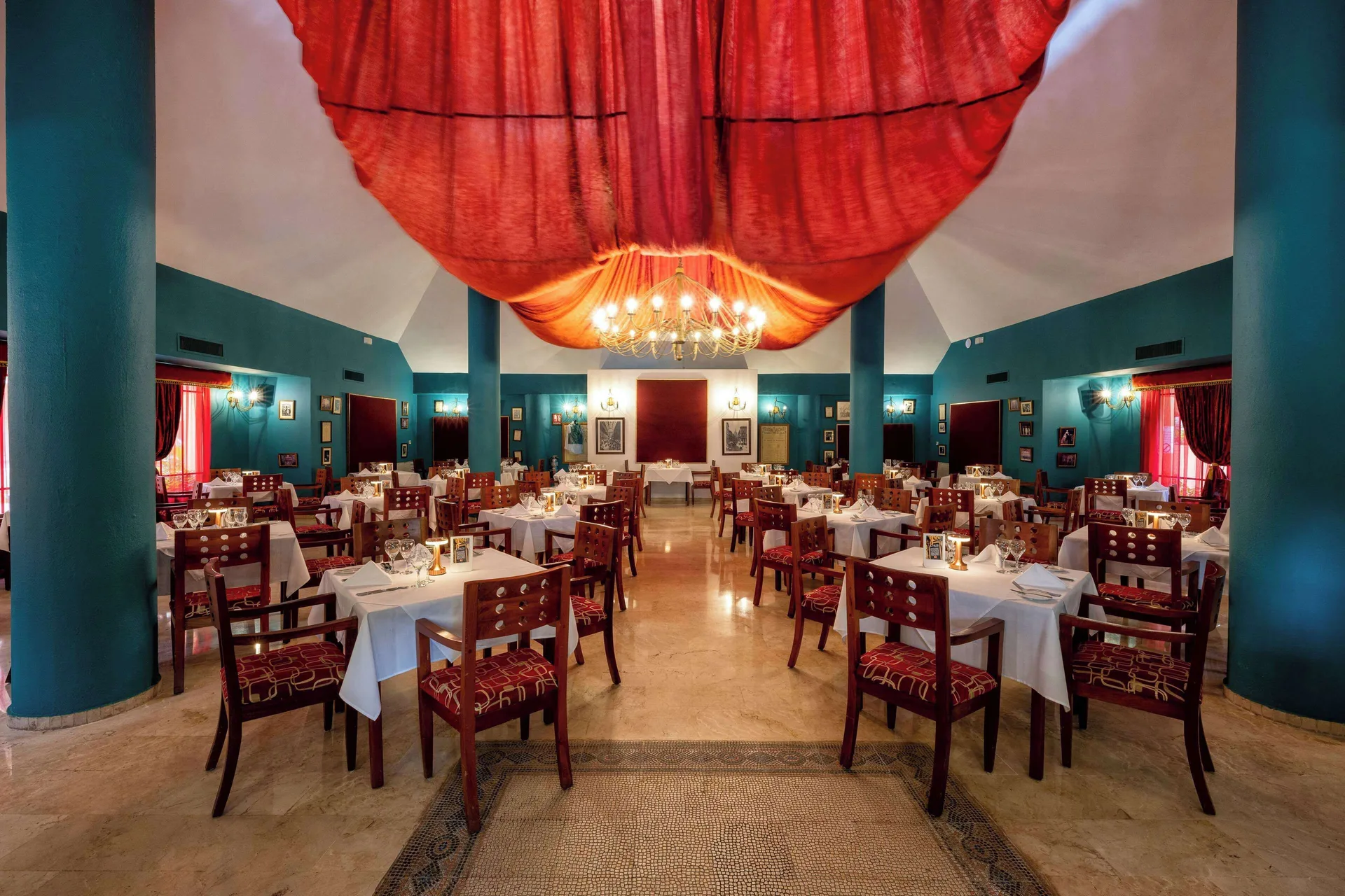 Formal dining room with teal walls and red draped ceiling at Viva Dominicus Palace.