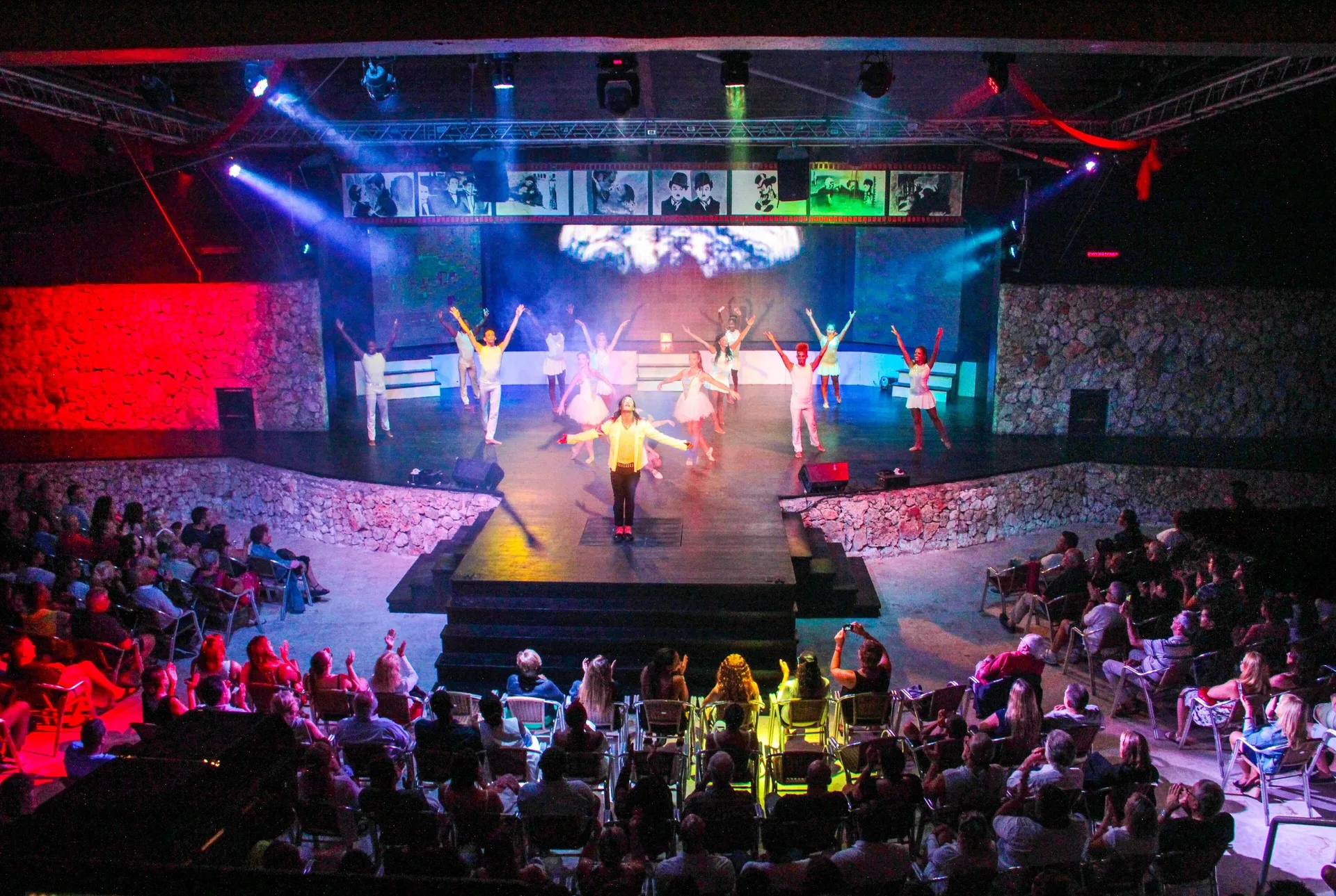 Performers dance on a lit theater stage at Viva Dominicus Palace.