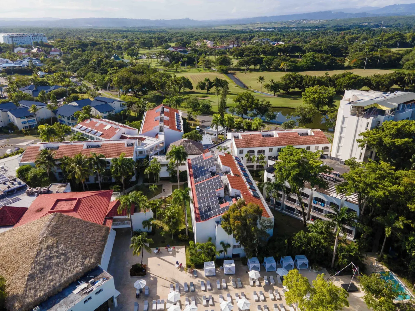 Aerial view of Viva Heavens rooftops, palms, lounge areas, and surrounding greenery.