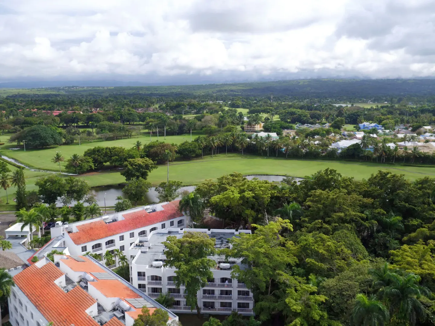 Aerial view of resort buildings, trees, and golf-like greens at Viva Heavens.